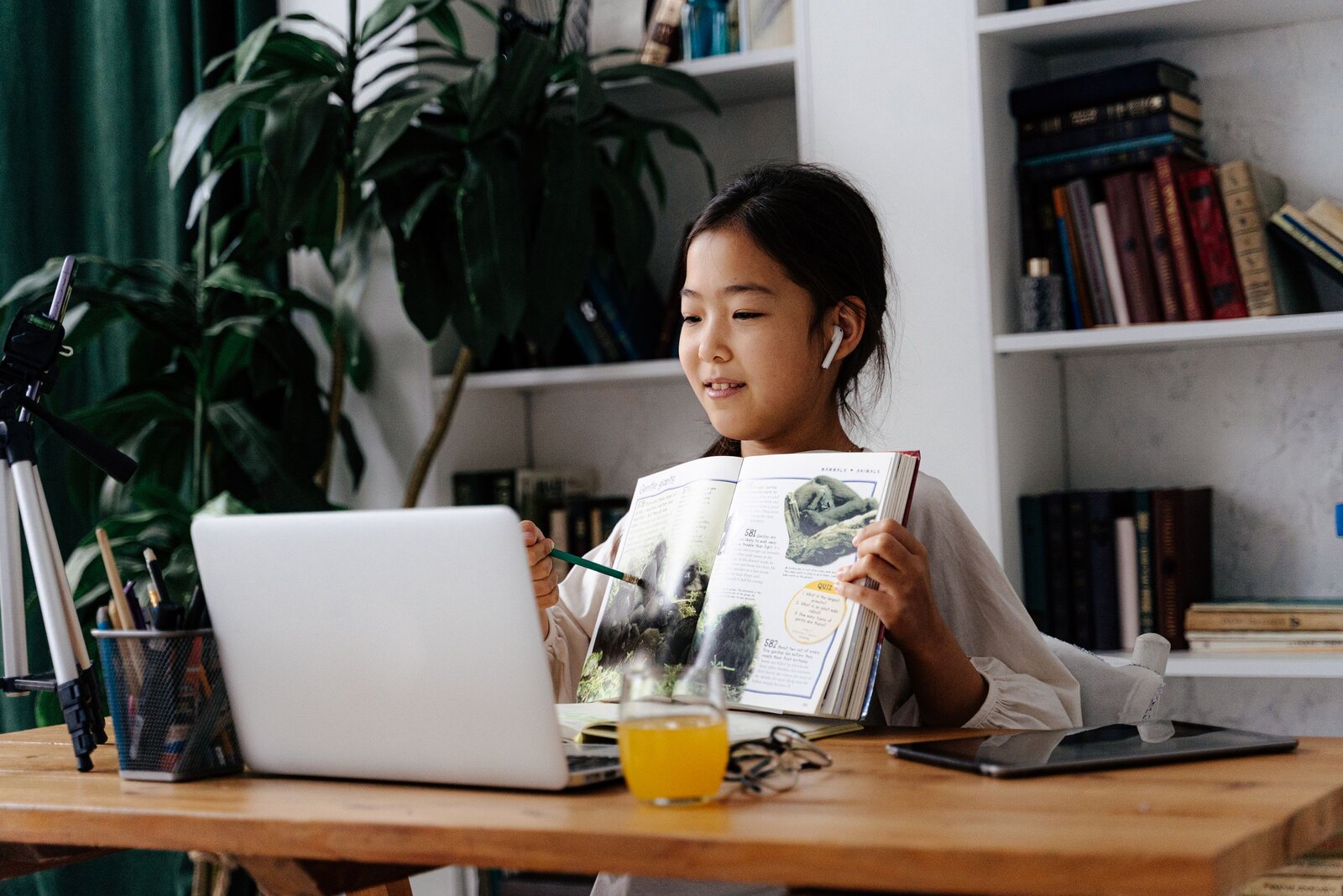 自宅の机で、本とノートパソコンを使って学ぶ子ども。