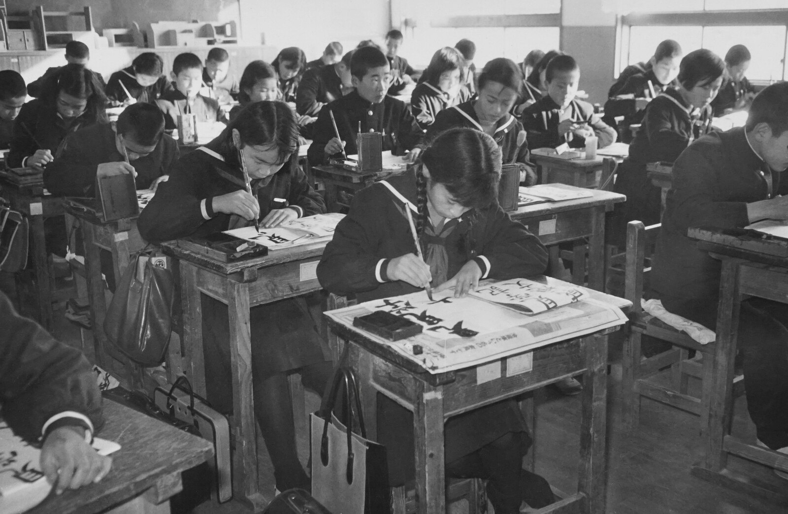 日本の学校の教室で、書道に取り組む生徒たち。